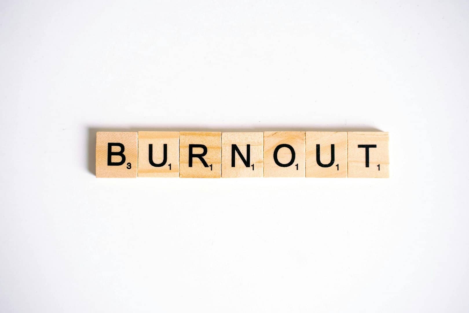 Conceptual image of 'Burnout' spelled with Scrabble tiles on a white background.